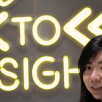 Insights - asian female standing on Welcome sign shop