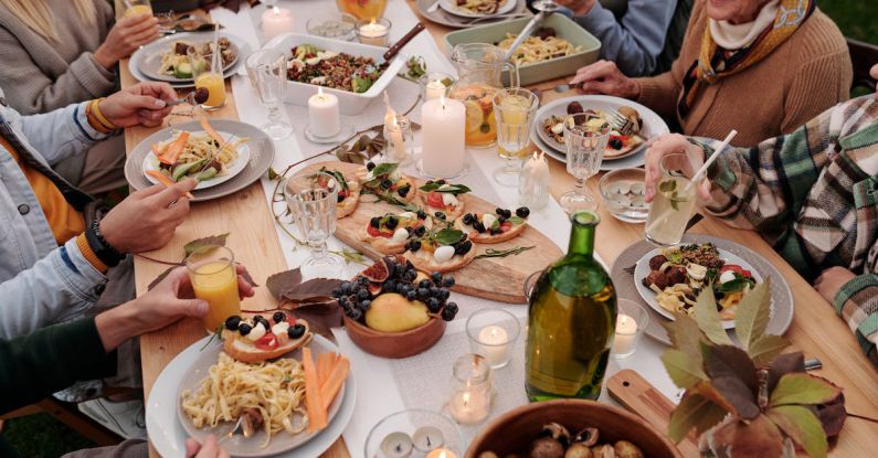 Family Reunions - From above crop people enjoying festive dinner with snacks at garden table with candles burning