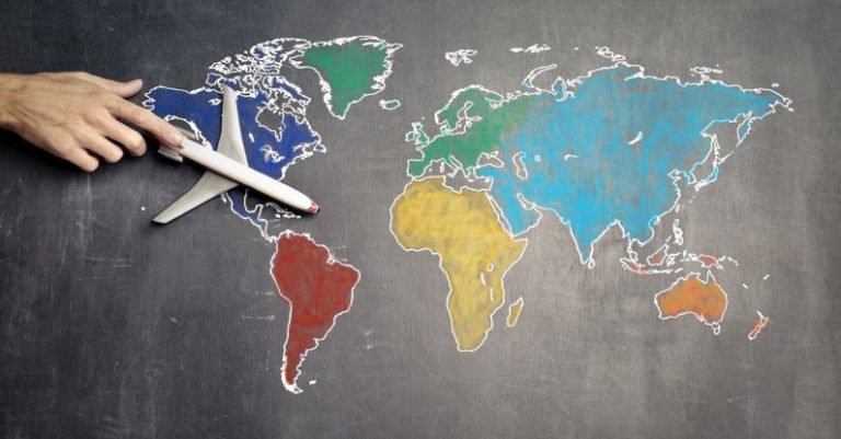 Educational Trips - Top view of crop anonymous person holding toy airplane on colorful world map drawn on chalkboard