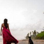 Beach Access - A woman in a red dress walking on the beach with a dog