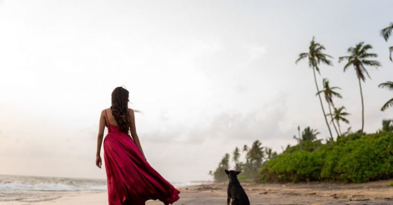Beach Access - A woman in a red dress walking on the beach with a dog