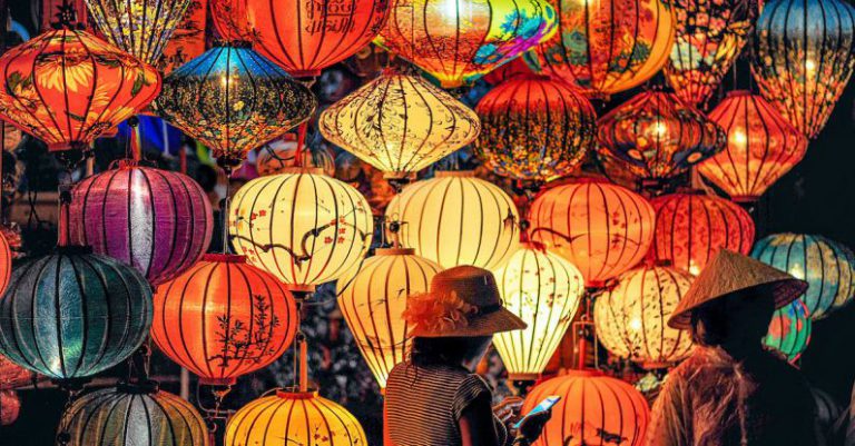 Culture - Two Person Standing Near Assorted-color Paper Lanterns