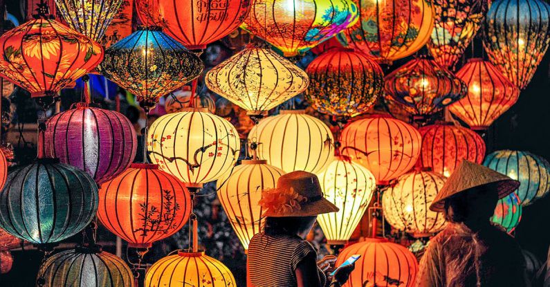 Culture - Two Person Standing Near Assorted-color Paper Lanterns