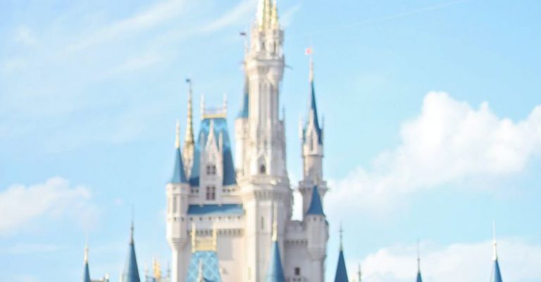 Romantic Excursions - White fairy tale castle with blue roofs in amusement park in Orlando against bright sky on sunny day